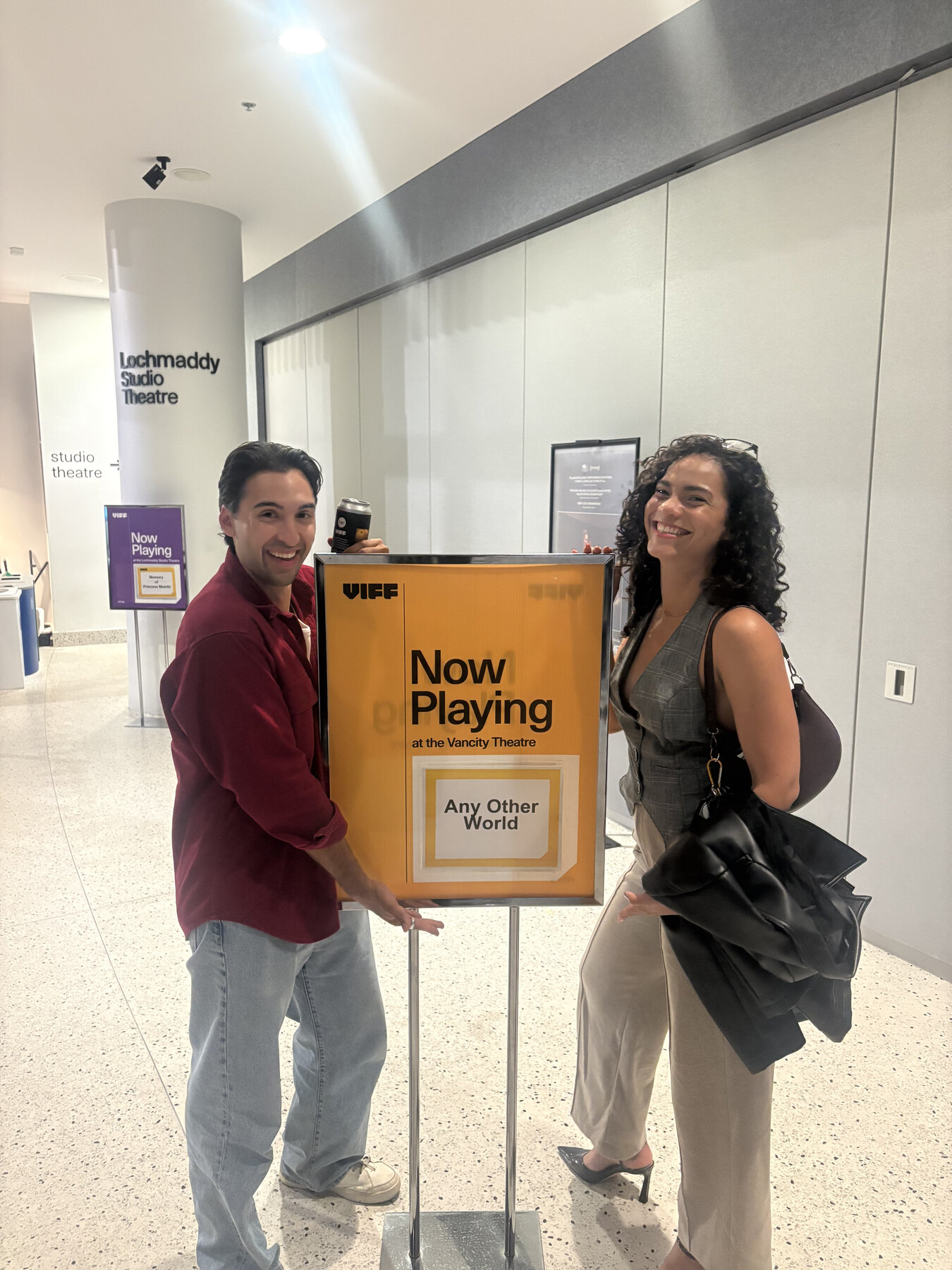 Santiago Henao and a cast member holding a Now Playing sign for Any Other World